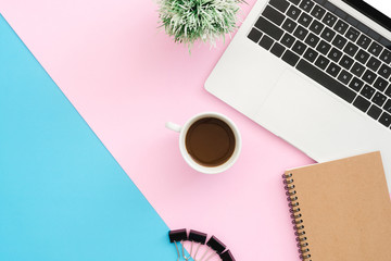 Creative flat lay photo of workspace desk. Top view office desk with laptop, clip, notebook, coffee cup and plant on blue pink color background. Top view with copy space, flat lay photography.