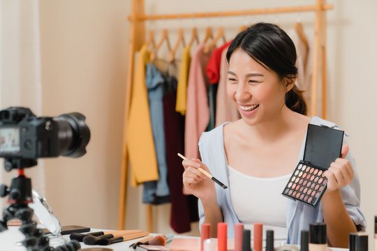 Beauty blogger present beauty cosmetics sitting in front camera for recording video. Beautiful asian woman use cosmetics review make up tutorial broadcast live video to social network by internet.