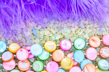 Fototapeta na wymiar Colorful Pearl Beads, Purple Bird Feather on Crystals of Bath Sea Salt for Spa