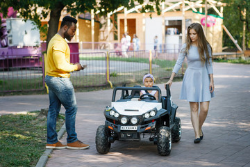 Little cute girl riding a toy car in the summer park on the track.
