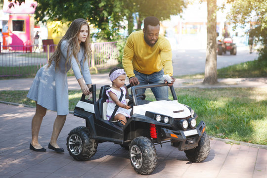 Little Cute Girl Riding A Toy Car In The Summer Park On The Track.