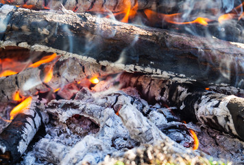 Campfire with burning firewood, close up. Glowing embers smoldering in the fireplace