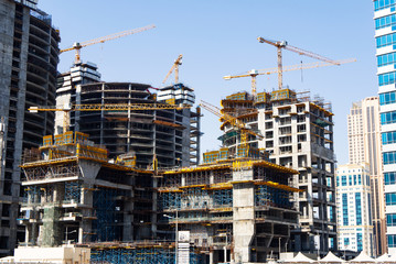 Four modern multistorey buildings under construction. Big construction with cranes and scaffolding