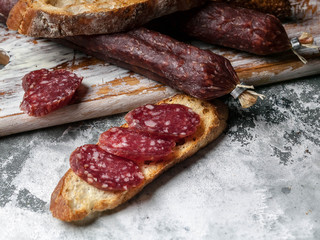 Smoked sausage sandwich on gray concrete background. Close-up.