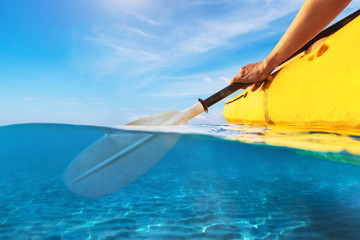 Split view of person kayaking in transparent blue sea, underwater and above water photography of...