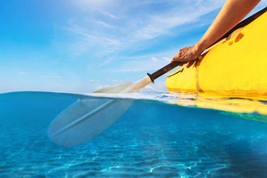 Split view of person kayaking in transparent blue sea, underwater and above water photography of kayak and paddle in warm summer tropical travel destination for vacation holidays