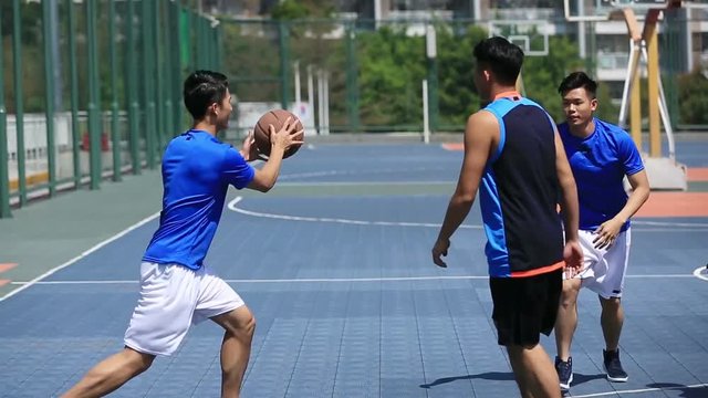 asian young adults playing basketball on outdoor court