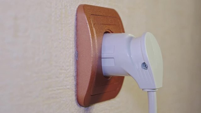 White electrical plug is inserted into the socket