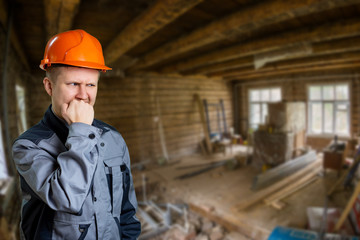 A builder engineer in an orange helmet is frightened by the amount of work. Construction site
