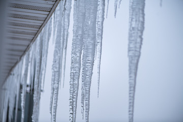 Icicles against the gray sky on the roof of the town house