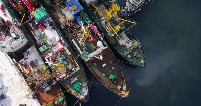 Top aerial view, flying above a few fishing boats moored near quay. Nevelsk, Sakhalin island, Russia. Tatar Strait, sea of Japan