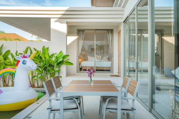 home or house  Exterior design showing tropical pool villa with greenery garden, sun bed, umbrella, pool towels and colorful floating unicorn