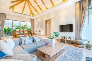 Luxury interior design in living room of pool villas. Airy and bright space with high raised ceiling and wooden dining table