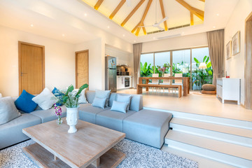 Luxury interior design in living room of pool villas. Airy and bright space with high raised ceiling and wooden dining table