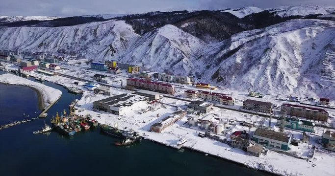 Aerial view of Nevelsk (Sakhalin island, Russia) situated between mountains and Tatar Strait, sea of Japan. Calm winter day. Mountains covered with snowy forests