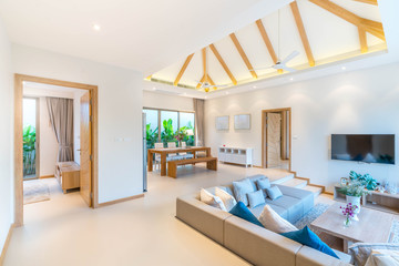 Luxury interior design in living room of pool villas. Airy and bright space with high raised ceiling and wooden dining table