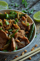 Asian food in a white bowl on a wooden background. Pasta with pork.