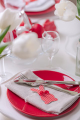 Happy easter. Decor and table setting of the Easter table is a vase with white tulips and dishes of red and white color. Easter colored eggs with white polka dots.