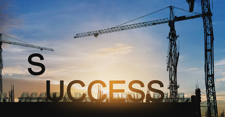 Success concept, Silhouette cranes and under construction building with SUCCESS  over sunset sky
