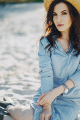 A beautiful young girl with curly hair and glasses on the beach by the water