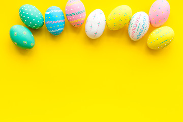 Easter composition. Decorated pastel Easter eggs on yellow background copy space border