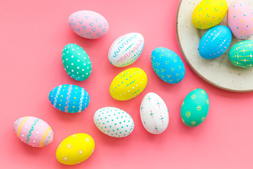 Festive Easter table. Colorful Easter eggs on plate on pink background top view space for text