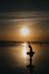 silhouette of girls on pier at sunset