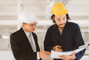 Asian engineers look at blueprint..