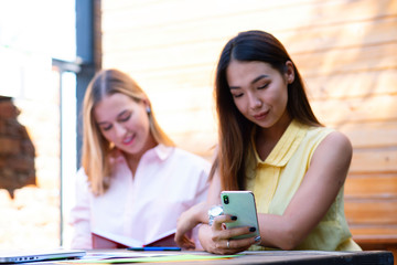 Two students sitting in a coffee shop while drinking coffee and using the lapyop computer. Two...
