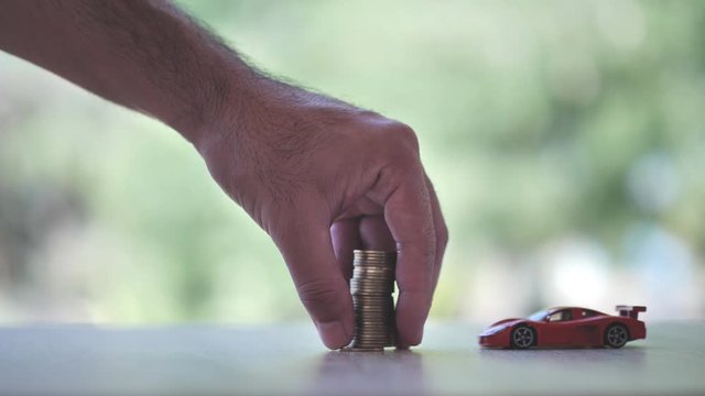 Hand putting money coins with car model on nature green background. Finance and car loan, refinance, Investment and business, Money exchange car concept. Slow Motion