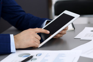 Businessman using tablet at meeting, closeup of hands. Business operations concept