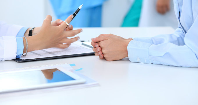 Doctor and patient discussing something, just hands at the table, white background