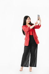Asian woman in casual dress holding smartphone selfie.