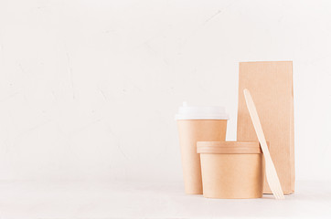 Set of cardboard package for different fast food for advertising, menu, banding identity - blank bowl for soup or ice cream, drink cup, packet, fork on white wooden background.