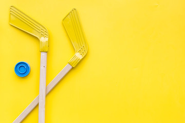 Ice hockey stick and puck on yellow background top view copy space