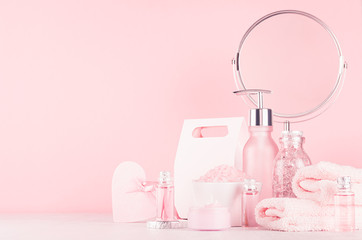 Modern girlish dressing table with pink cosmetics products and accessories, round mirror, box on soft white wood table, copy space.