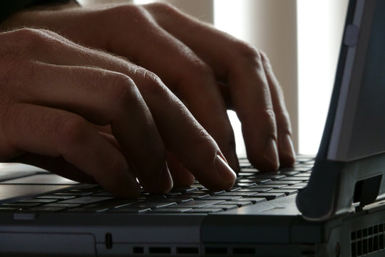 Male Hands Up Close Typing on a Laptop Computer Keyboard in an Office