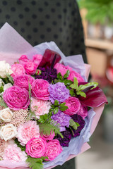 ombre of color. beautiful fresh cut bouquet of mixed flowers in woman hand. the work of the florist at a flower shop. Delicate Pastel tones color