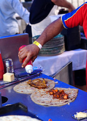 Indian street food vendor make vegetable roll or frankie, adding sauce