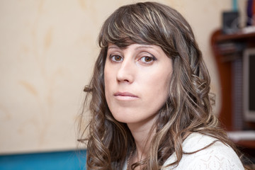 Sad young woman portrait, brown eyes, curly dark hair, face with make-up, looking at camera