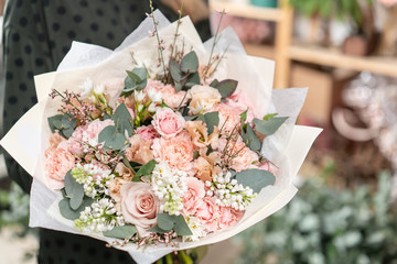 beautiful fresh cut bouquet of mixed flowers in woman hand. the work of the florist at a flower shop. Delicate Pastel tones color