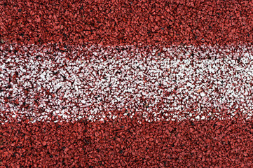 Close-up view at red rubber running line with horizontal white stripe in the middle, background