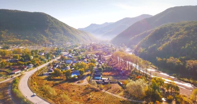 Ascending aerial view of small city Dalnegorsk (far in the mountains) in Russian Far East. It's situated in the heart of Sikhote-Alin mountains range. Beautiful landscape with road and driving cars