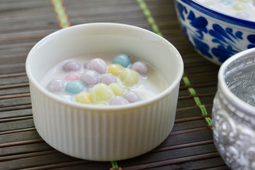 Color of Rice Dumpling in Coconut Milk (Bua Loy) in white bowl on wooden table for served in party. Famous dessert in Thailand. Sweet and delicious food.
