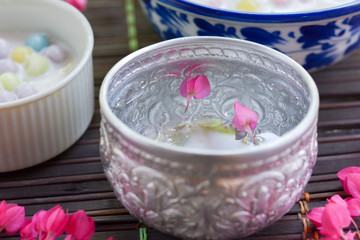 Pink flower float on clear water in Thai metal glass.