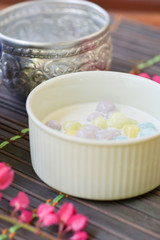 Color of Rice Dumpling in Coconut Milk (Bua Loy) in white bowl on wooden table for served in party. Famous dessert in Thailand. Sweet and delicious food.