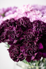 beautiful carnations flowers in a vase on a table . Bouquet of dark violet, purple and pink multicolor flower. Decoration of home. Floral texture, Wallpaper.