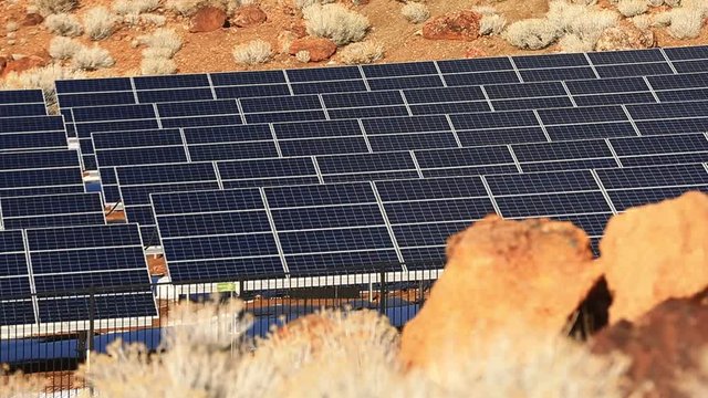 Pan of Solor Panels in Desert with Red Rocks - Shallow Depth of Field.