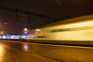 Naklejka na ściany i meble Train in motion on the station at night, long exposure photo.