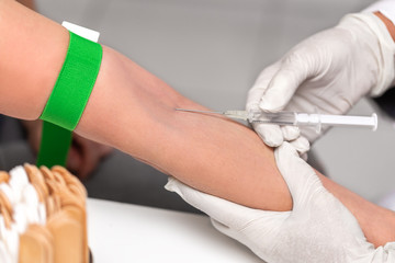 Arzt gibt eine intravenöse Spritze, Venenstauer um den Arm
